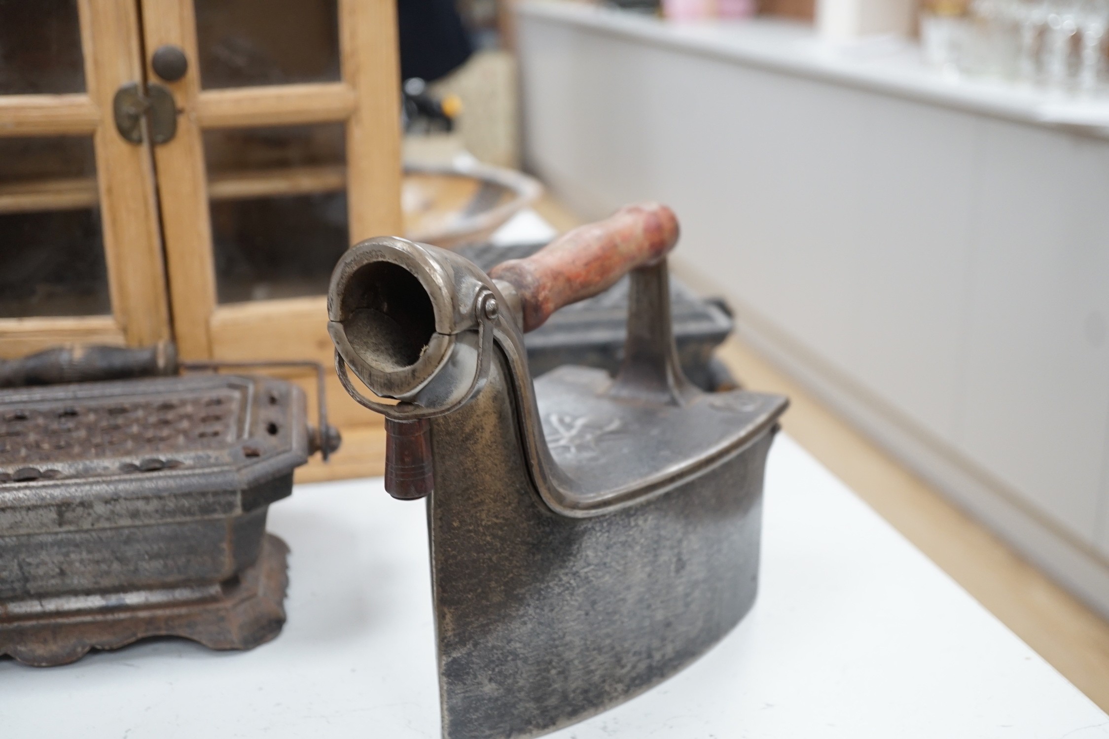 Four French coal/slug irons, three trivets and a stripped pine glazed cabinet, 37cm high